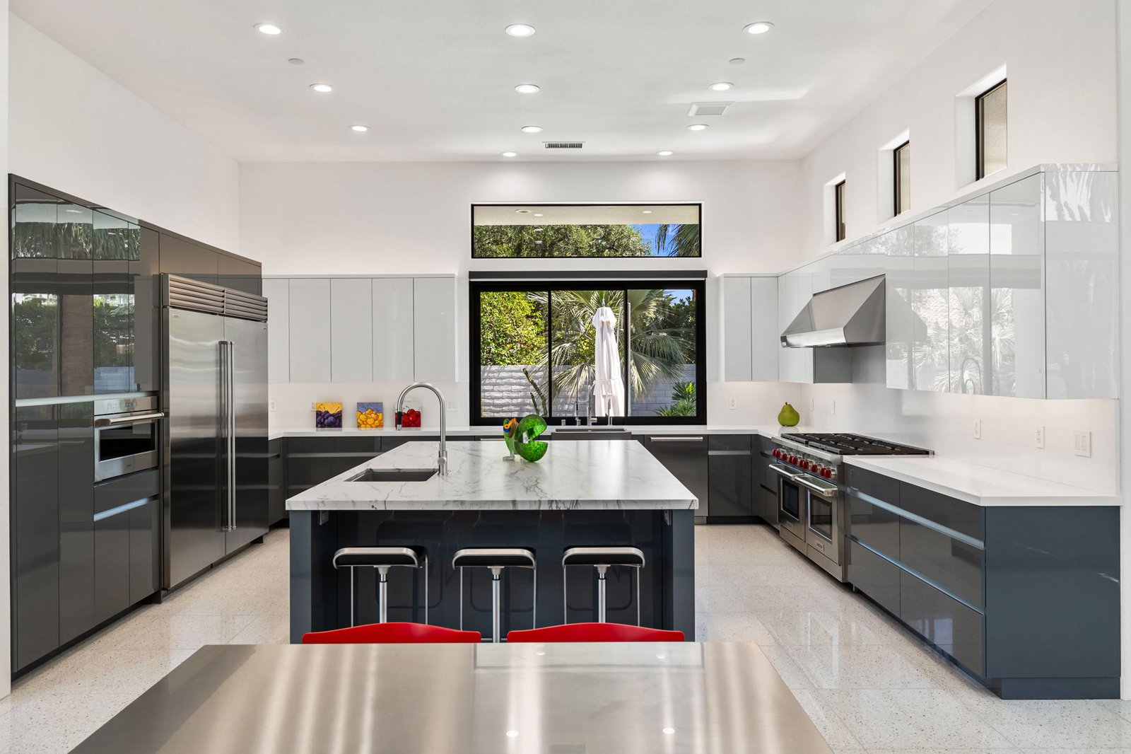 Wide kitchen with two-tone slab cabinetry, waterfall island, barstools, and Sub-Zero, Rancho Mirage