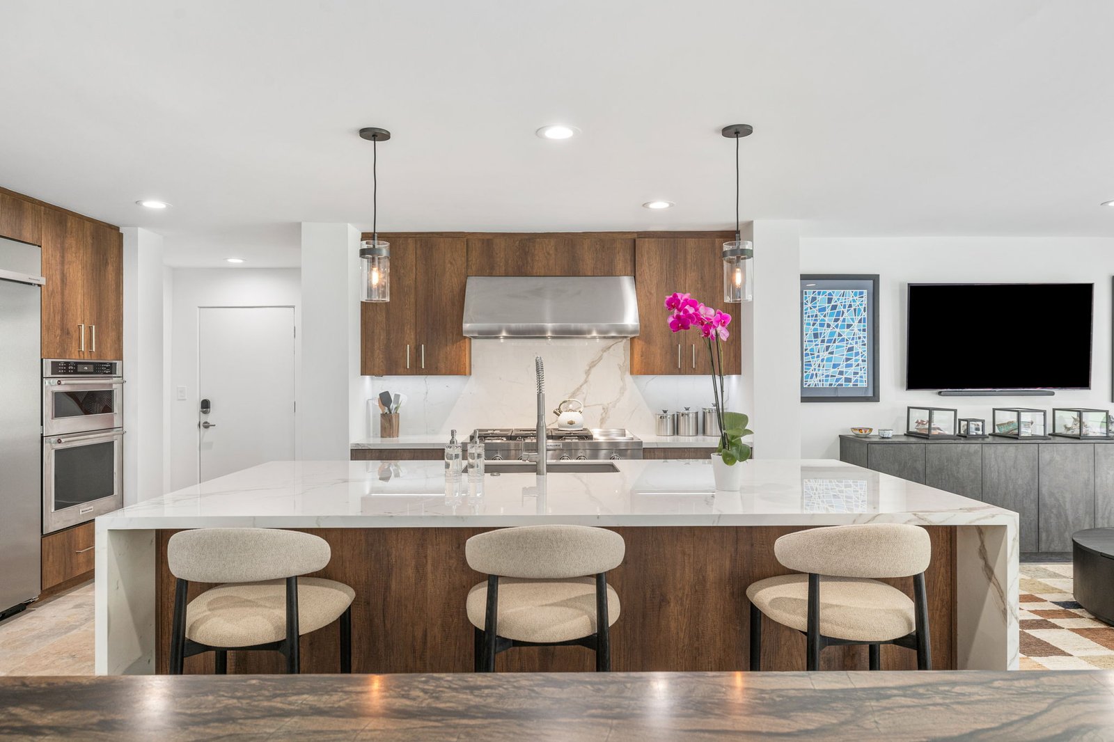Whole-home overview with walnut kitchen cabinets, marble island, and charcoal living room credenza beyond