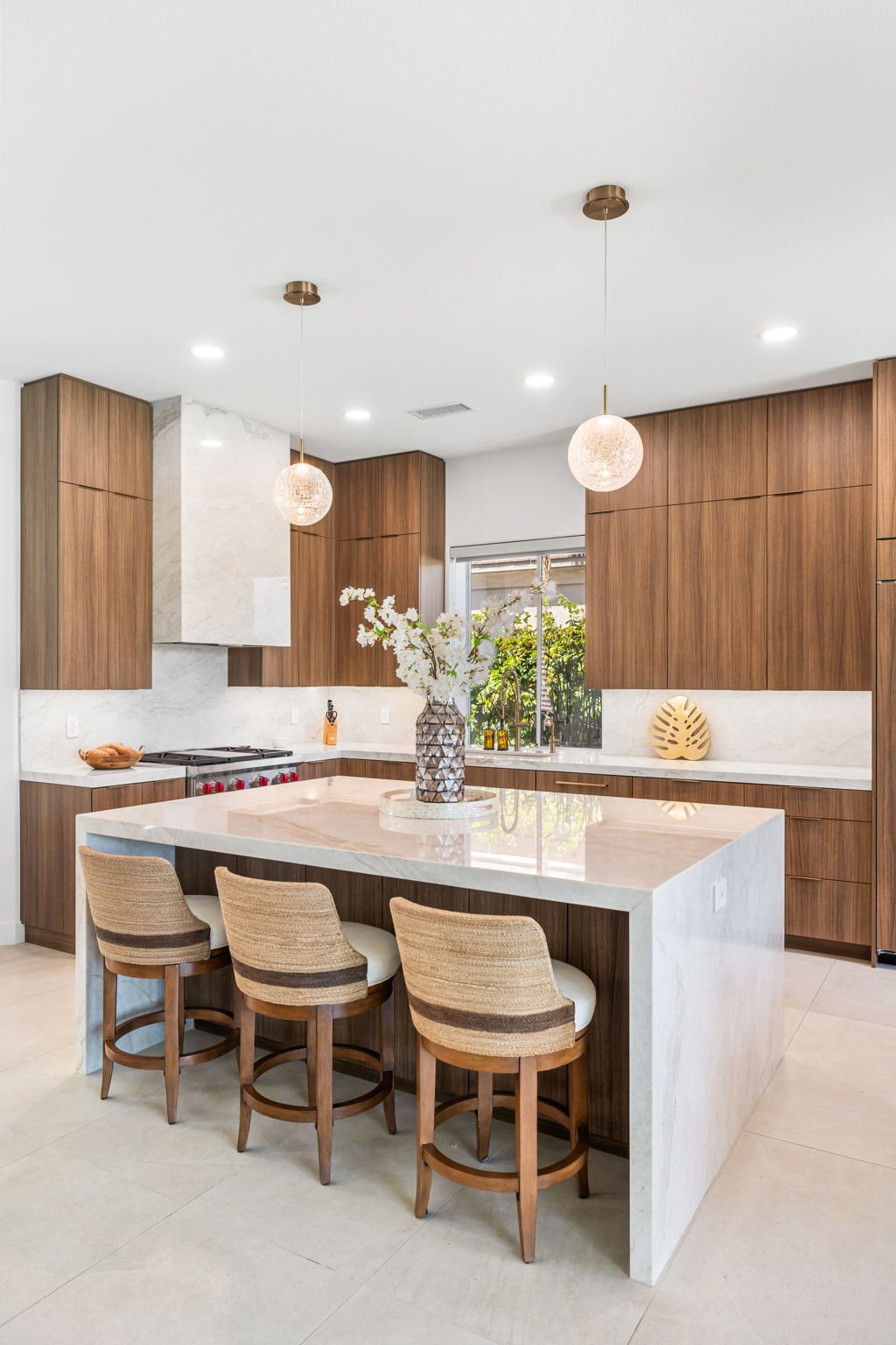 Waterfall marble island with barstool seating, pendant lighting, and custom cabinetry Rancho Mirage
